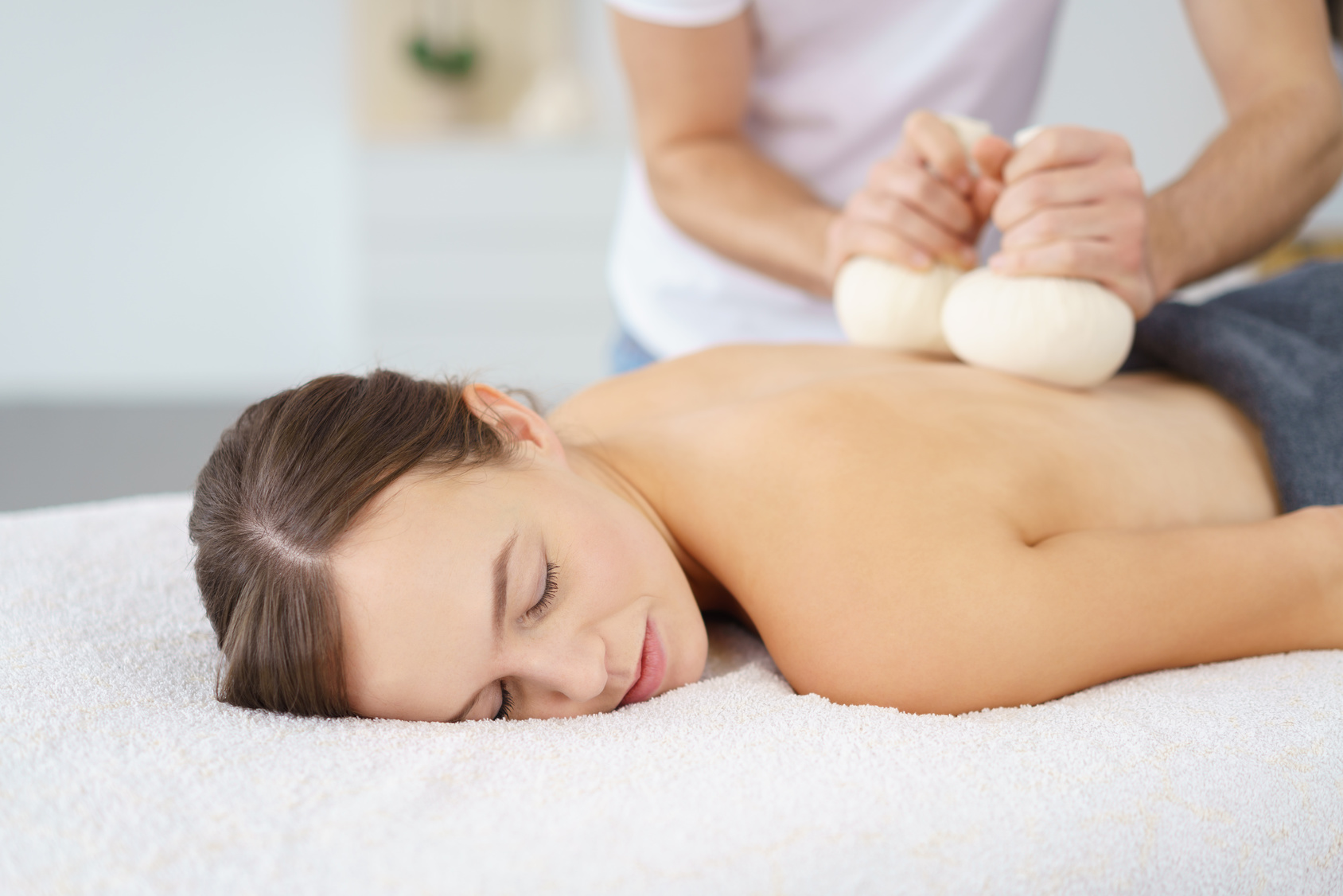 frau entspannt bei einer massage mit kruterstempeln